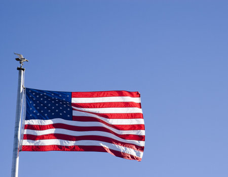 An American Flag waving in the wind against a blue skyの写真素材