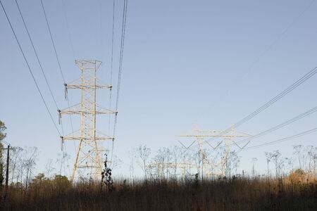 An empty field covered with high power lines and towers at dawnの写真素材