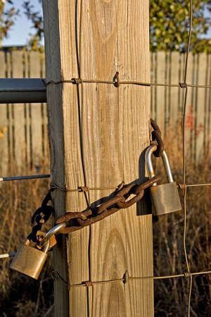 Old locks and a rusty chain on a post and fenceの写真素材