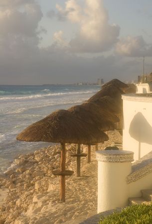 A row of straw and bamboo umbrellas in a row down the beachの写真素材