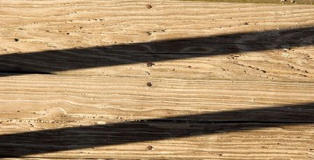 Shadows running across old weathered, sandy planks on a beach boardwalkの写真素材