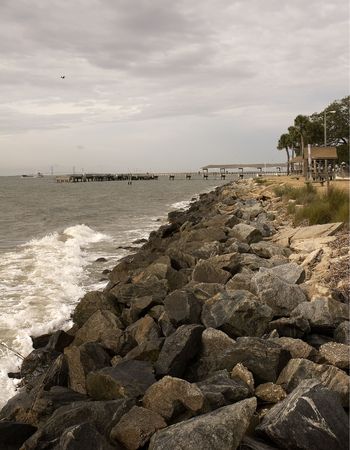 A rocky shore line leading to a distant pierの写真素材
