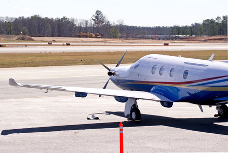 A red, yellow, and blue propeller driven plane on the tarmac at an airport