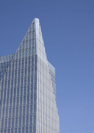 A modern glass office tower with a pyramid shape at the topの写真素材