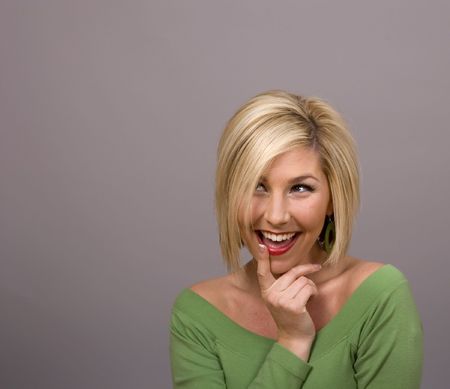 A young blonde in a green blouse with her finger on her lipsの写真素材