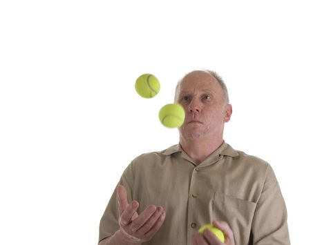 An older guy in a brown shirt juggling green tennis ballsの写真素材