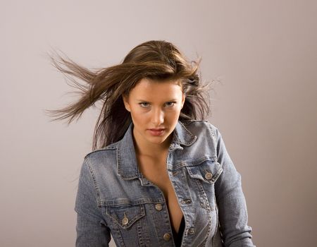A beautiful young brunette with her denim jacket open exposing a black bra and her hair blowing in the windの写真素材