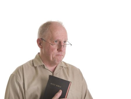 An old man in glasses holding a bible and looking of to the side with sad lookの写真素材