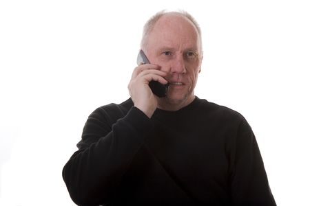An older guy in a black shirt talking on a cell phone with a serioius expressionの写真素材