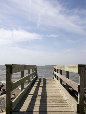 An old weathered bridge across a seawall toward the ocean.の写真素材