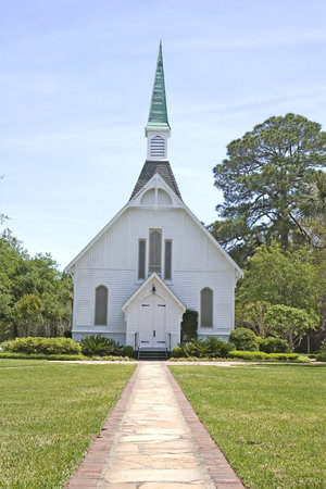 A brick path through a green lawn to a small white churchの写真素材