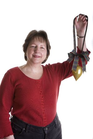 A nice woman in red holding a gold Christmas ornament on plaid ribbonの写真素材