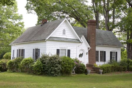 An old farmhouse with siding and a brick chimneyの写真素材