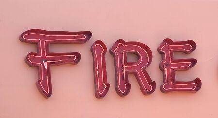 A red neon sign on a pink wall showing Fireの写真素材
