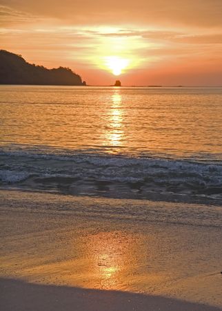 A beautiful orange sunset reflected in the wet sandの写真素材