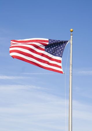 An american flag against a blue sky with hazy cloudsの写真素材