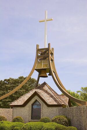 A bell tower and a cross on a display in a public parkの写真素材