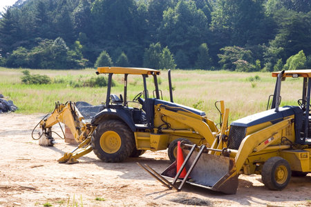 Two pieces of heavy construction equipment in a field ready for development