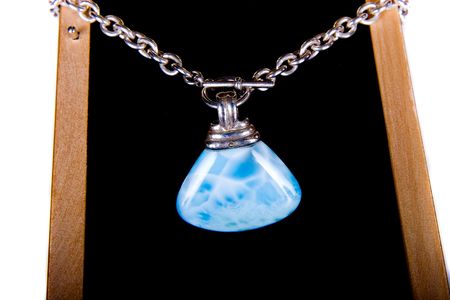 A blue lapis stone on a silver chain on black velvetの写真素材