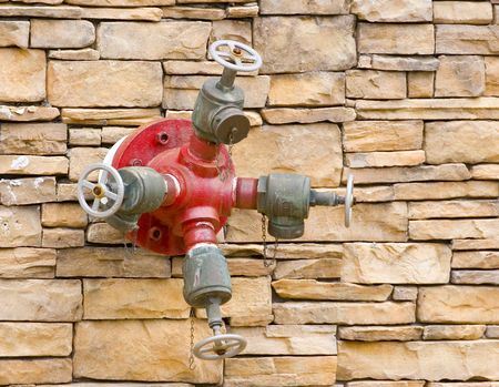 A red fire hydrant on a rock masonry wallの写真素材