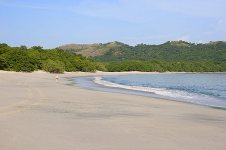 A lone runner in the distance on a deserted beach