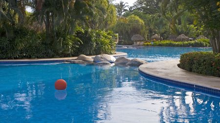 A red ball floating in a blue tropical poolの写真素材