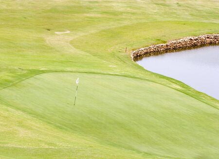 A green on a golf course with flag next to a water trapの写真素材
