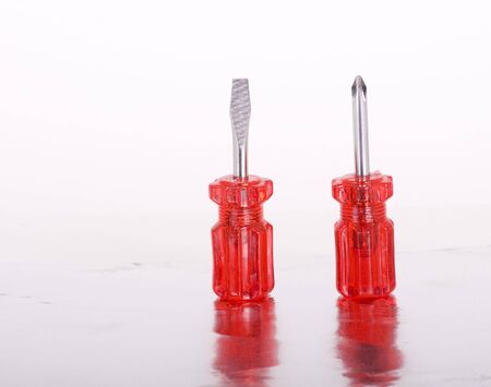 Two screwdrivers with red handles on white and aluminum foilの写真素材