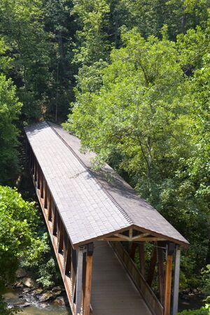 An old covered bridge over a stream in the woodsの写真素材