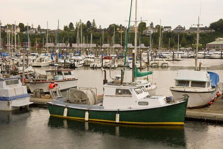 An old green fishing boat in a harbor in the rainの写真素材