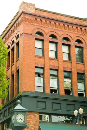 An old brick building with green wood trim and a clockの写真素材