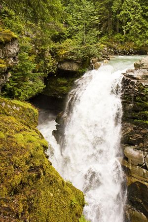 A waterfall past a cliff covered with moss and lichensの写真素材