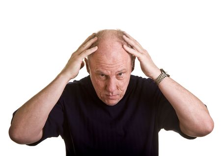 An older man leaning over with his hands on his bald headの写真素材