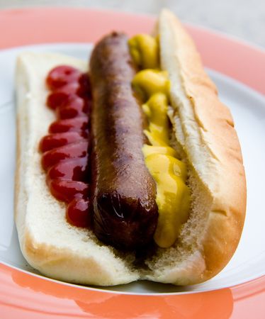 A hot dog on a plate with mustard and ketchupの写真素材
