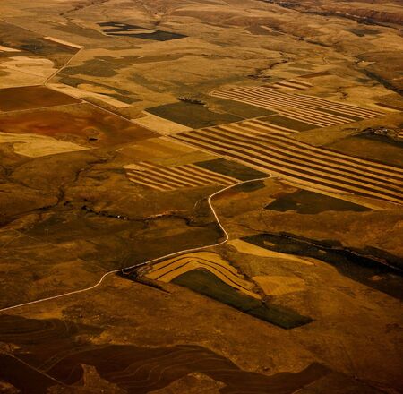 A road through cultivated farmland from aboveの写真素材