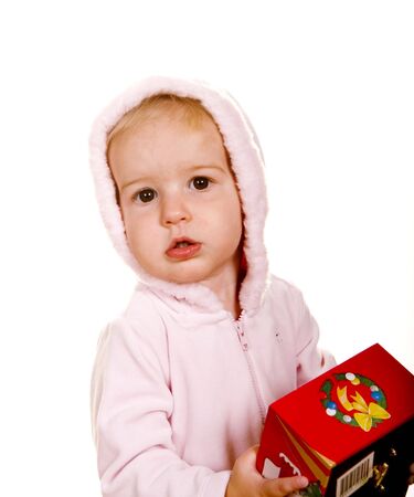 A baby in a pink jacket holding a red Christmas giftの写真素材