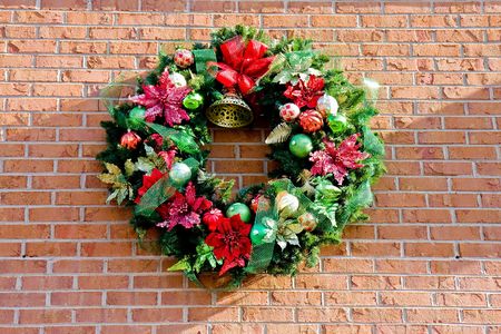 A christmas wreath on a brick wall in the sunlightの写真素材