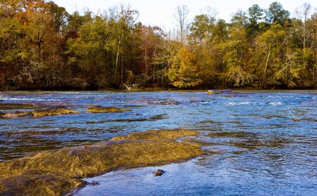 A river in the fall reflecting the blue skyの写真素材
