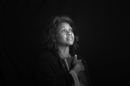A spiritual black woman holding a bible and looking toward heavenの写真素材