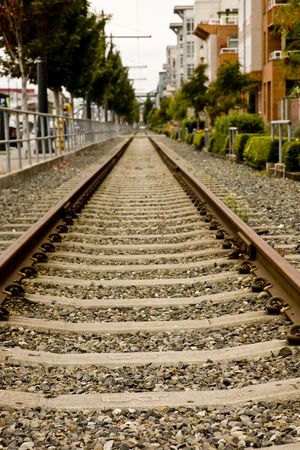 Railroad tracks running straight alongside a city streetの写真素材