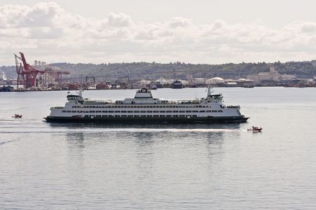 A large ferry crossing a busy industrial harborの写真素材
