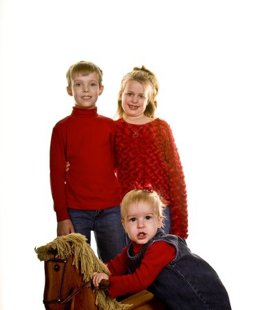 A young boy and girl and a toddler posing on white with a generic rocking horseの写真素材