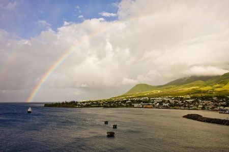 A rainbow in the morning clouds off of a lush green islandの写真素材
