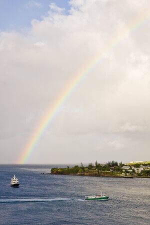 Two ferries cruising between islands under an early morning rainbowの写真素材