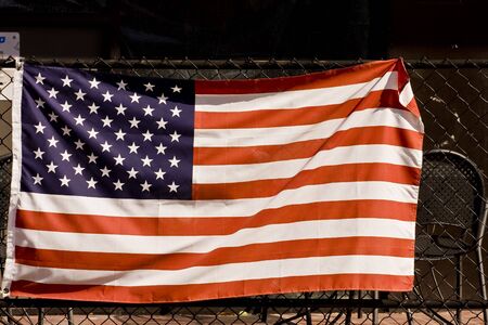 An American Flag on a fence in front of a businessの写真素材