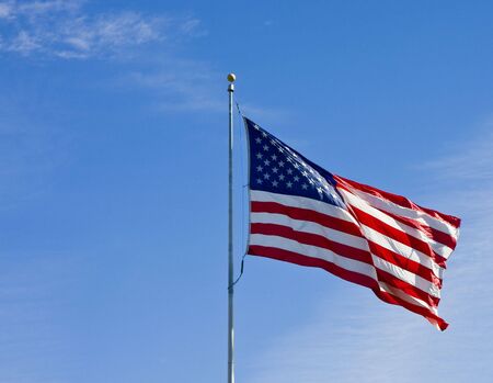 An American Flag blowing in a light wind against a blue skyの写真素材