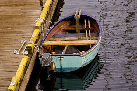 An old blue fishing boat tied to a yellow pierの写真素材