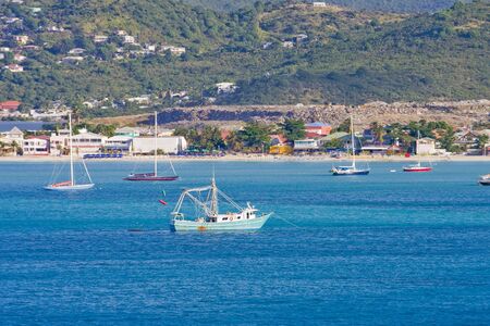 Blue boats tied up in a blue bay off of an islandの写真素材