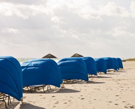 Blue Beach Shelters and Umbrellas on a beach on a cloudy dayの写真素材