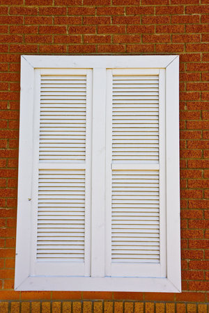 WhiteLouvered window on a red brick wall